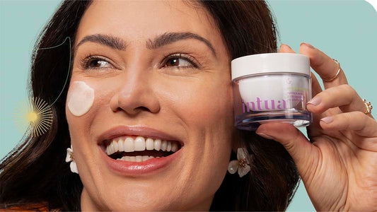 mulher segurando um pote do Creme Nutritivo Facial da Intua com um pouco do produto aplicado em seu rosto