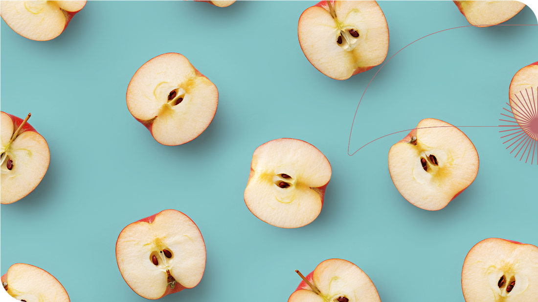 Várias maçãs cortadas ao meio sobre uma superfície azul.