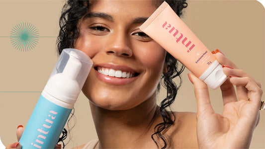 mulher sorrindo segurando a Espuma de Limpeza Facial e o Esfoliante Facial da Intua sobre seu rosto