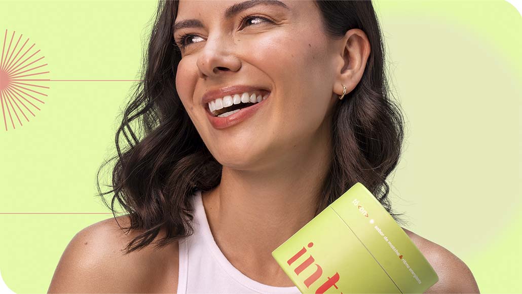 mulher sorrindo segurando um pote de Chá Infusão Tô On Energizante da Intua