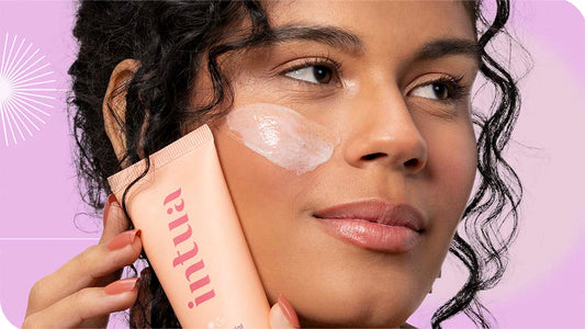 mulher segurando o Esfoliante Facial da Intua contra o rosto, com um pouco do produto aplicado em sua bochecha