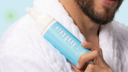 homem de roupão segurando um frasco da Espuma de Limpeza Facial da Intua