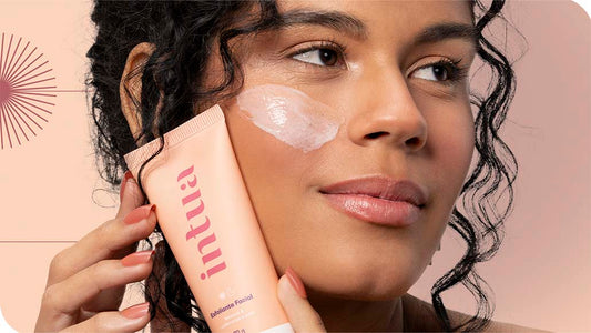 mulher segurando o Esfoliante Facial da Intua contra o rosto e um pouco do produto está aplicado em sua bochecha