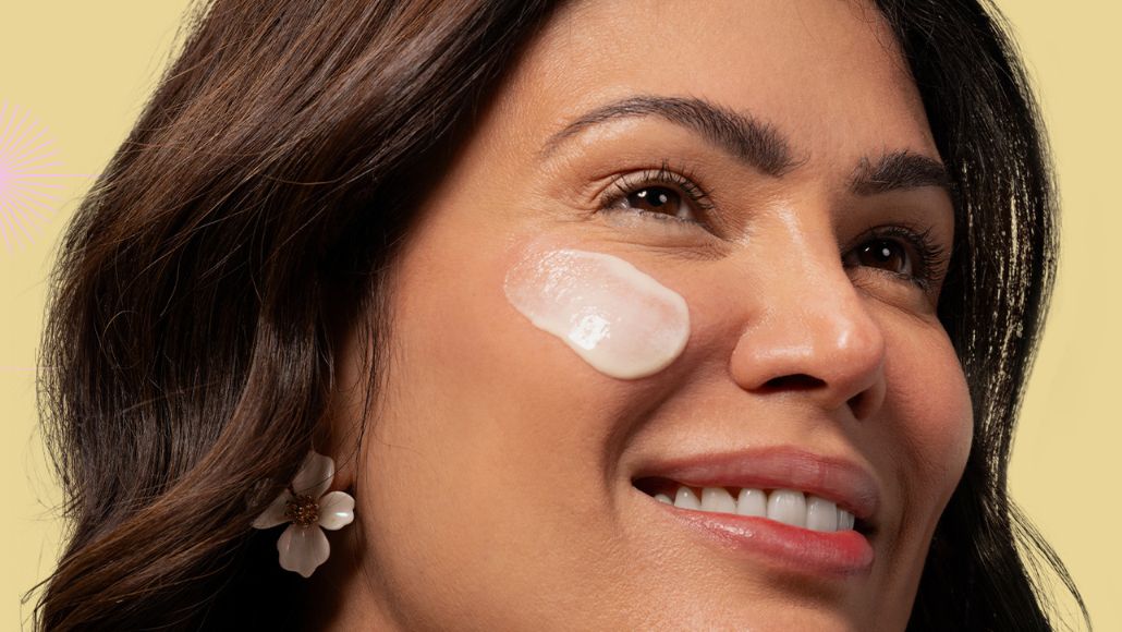 Mulher com o Creme Nutritivo Facial da Intua aplicado em sua bochecha.