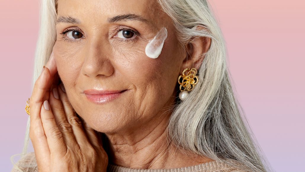 Mulher mais velha com o Creme Nutritivo Facial da Intua aplicado em sua bochecha.