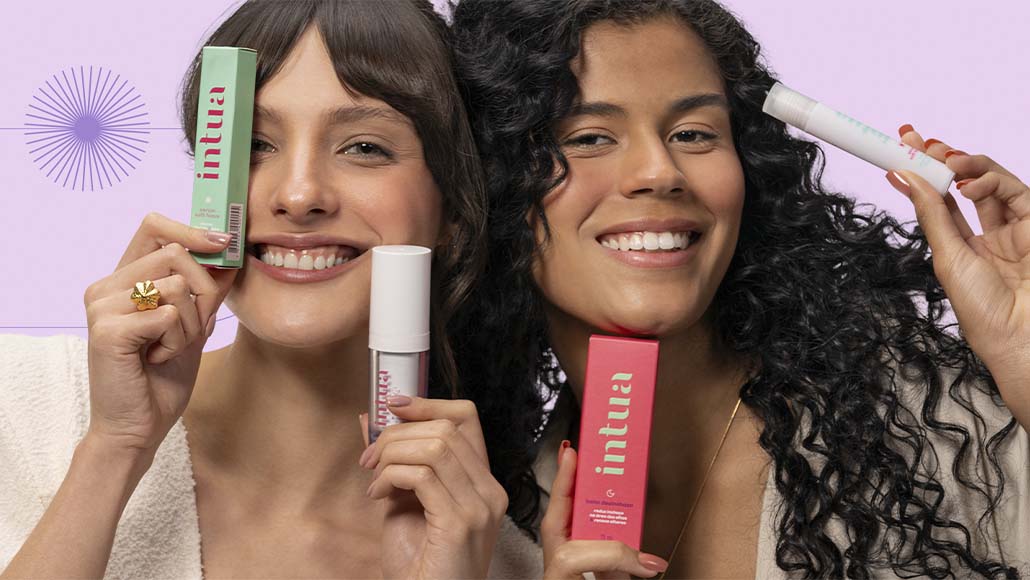 duas mulheres sorrindo segurando diversos produtos de skincare da Intua