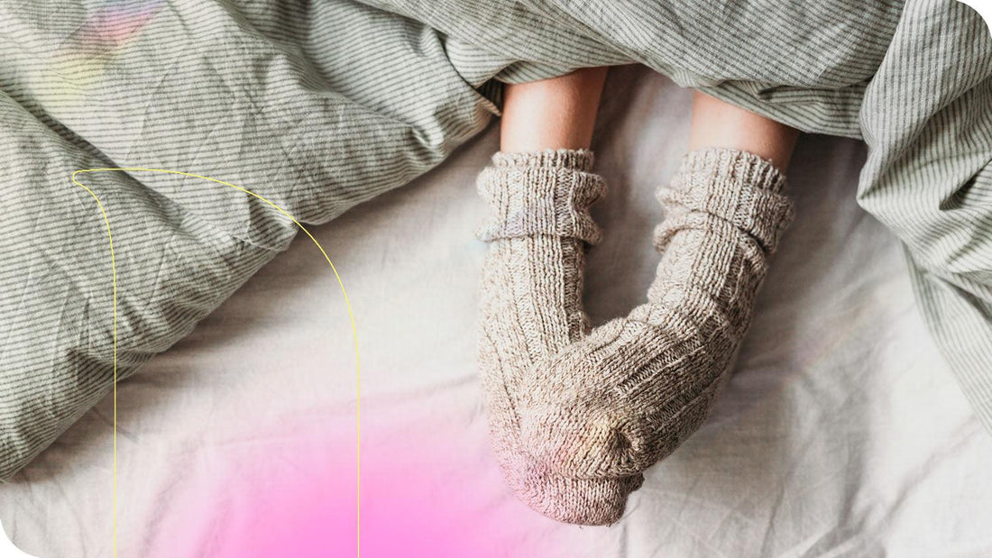 mulher vestindo meias com os pés para fora do cobertor